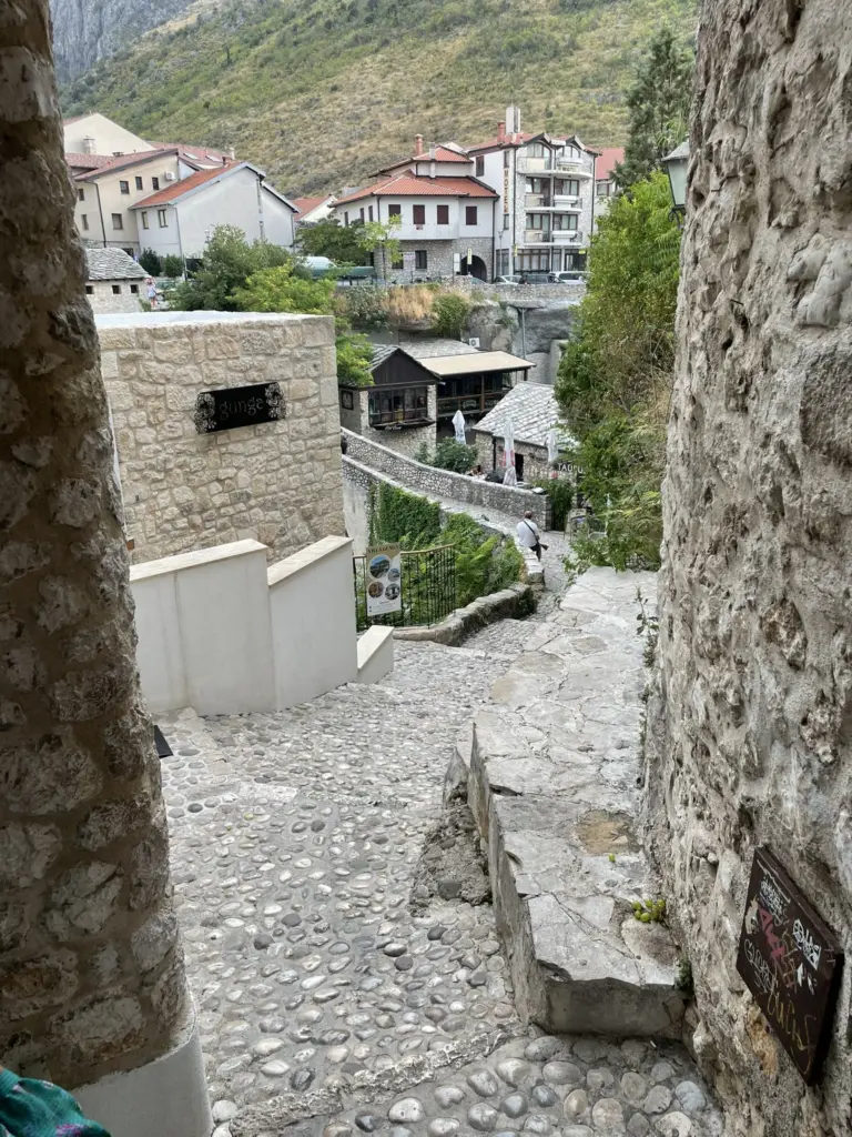 Ruelles étroites et pavées de Mostar, bordées de maisons traditionnelles en pierre et décorées de fleurs, avec une ambiance authentique et pittoresque.