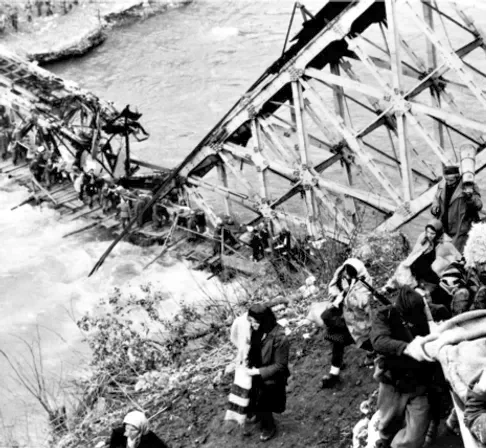 Photo historique montrant des partisans traversant la rivière Neretva sur le pont détruit de Jablanica en 1943, pendant la bataille de la Neretva.