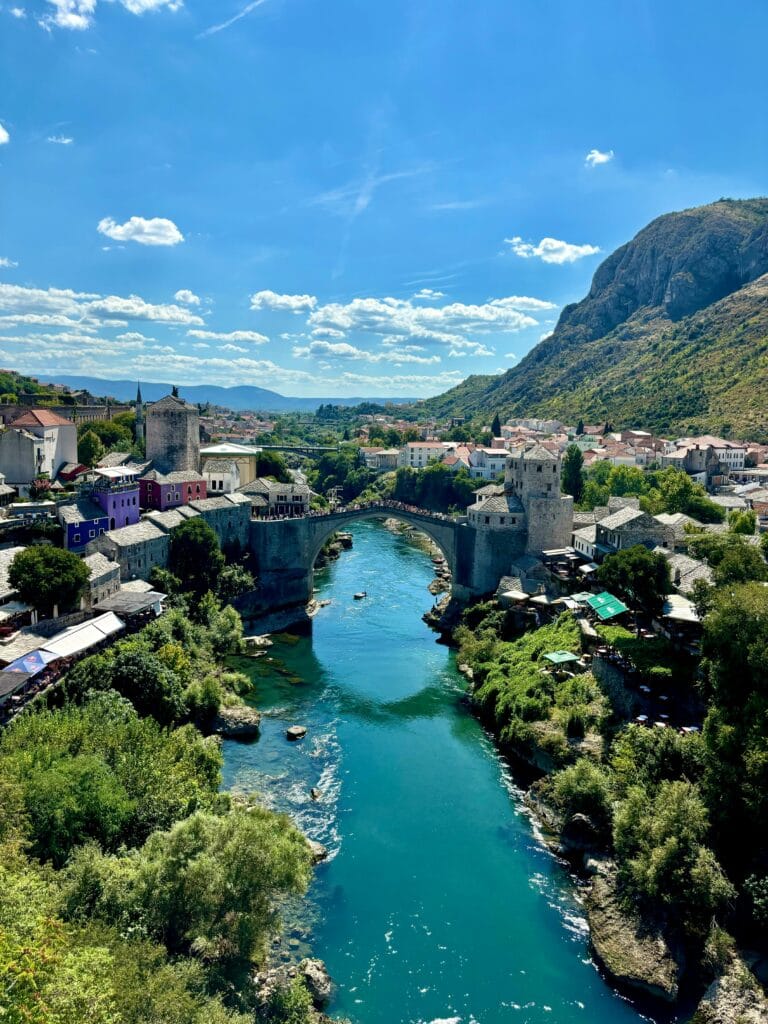 Le célèbre pont de Mostar en Bosnie, surplombant la rivière Neretva, entouré de bâtiments historiques et de visiteurs.
