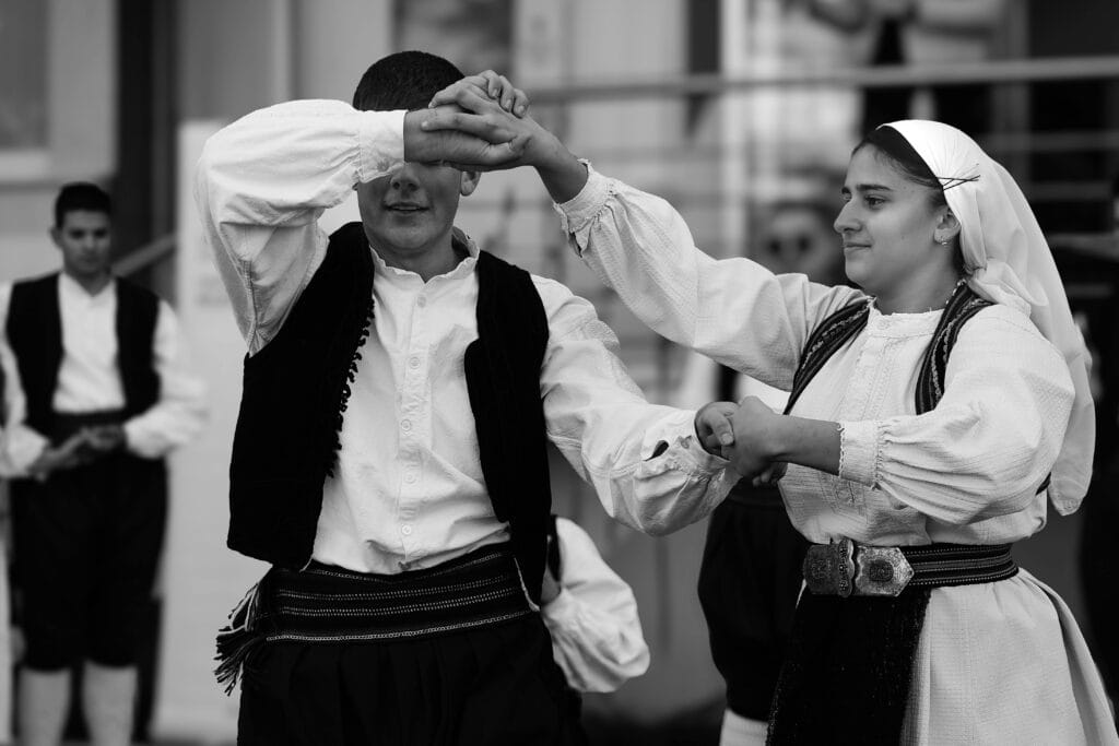 Des danseurs traditionnels en costumes colorés exécutent une danse en plein air à Sarajevo, des traditions qui perdure.