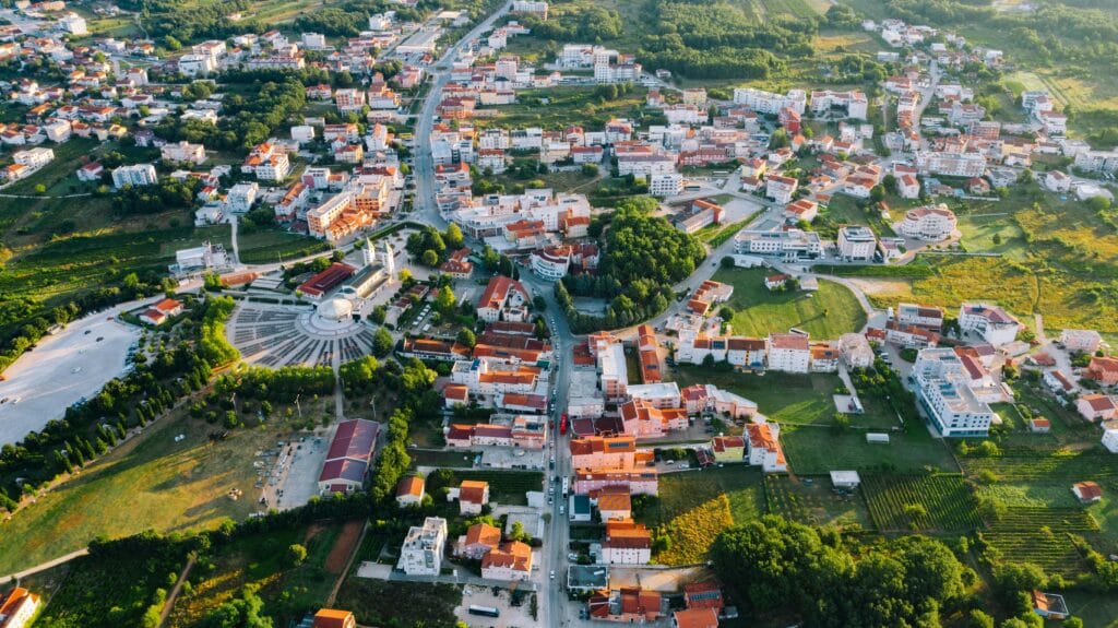 Vue aérienne de Međugorje montrant le village, les collines et l’église centrale.